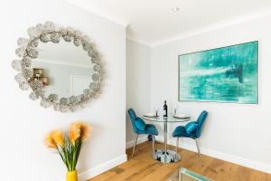 a dining room with a round mirror and blue chairs at Boutique Basement 1 Bed Flat, central location, free parking, Wi-Fi, Sky, Netflix in Leamington Spa