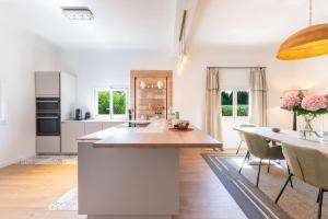 une cuisine blanche avec une table et une salle à manger dans l'établissement Maison Tropézienne en plein centre avec jardin et piscine, à Saint-Tropez