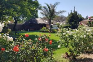 a garden with flowers and a thatched hut at Alberton Guest House in Alberton