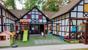 a building with a playground in front of it at Domki Tutti Frutti in Pobierowo