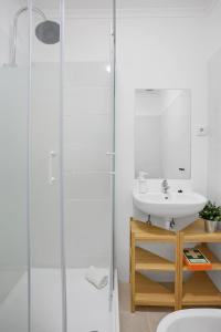 een witte badkamer met een wastafel en een douche bij One bedroom Apt in Almada with River view! in Almada