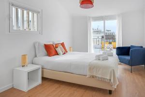 een witte slaapkamer met een bed en een blauwe stoel bij One bedroom Apt in Almada with River view! in Almada