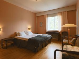 1 dormitorio con 1 cama, 1 silla y 1 ventana en Myllykosken Kerho Oy, en Kouvola