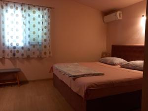 um pequeno quarto com uma cama e uma janela em Mitan apartman em Tučepi