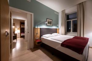 a bedroom with a large bed with a red blanket at Hotel Stiegl Scala in Bolzano
