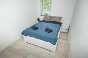 Happyland Villa, Jablanica في Jablanica: غرفة نوم بيضاء مع سرير وبطانية زرقاء