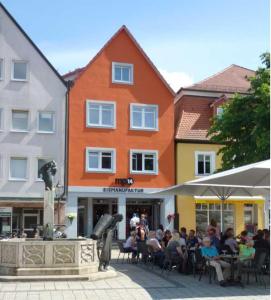 a group of people sitting at tables in front of a building at Stadtapartments am Marktplatz in Ebermannstadt