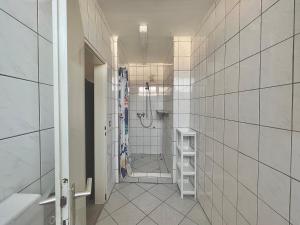 uma casa de banho em azulejos brancos com um chuveiro e uma cabina de duche ao nível do chão em Monteurwohnung in Stadtnähe em Hanôver