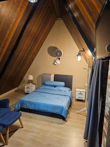 a bedroom with a blue bed in a attic at Orkid Chalet in Cameron Highlands