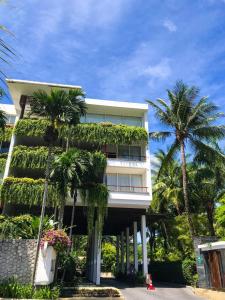 um edifício com palmeiras em frente em Beachfront 2 BR Luxury Apartment Chava Surin em Praia de Surin