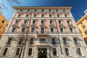 a large pink building in the middle of buildings at Rose Garden Palace Roma by OMNIA hotels in Rome