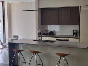 a kitchen with a sink and bar stools at Portonovi - Marina Residences Sea View Apartment in Herceg-Novi