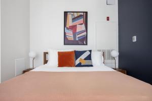 a bedroom with a large bed with orange and blue pillows at South Boston studio w wd nr red line BOS-886 in Boston