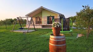 a house with a swing and a flower pot on a barrel at Kuća za odmor Neli in Sukošan