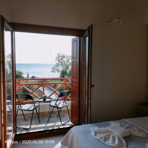 a bedroom with a bed and a balcony with a table and chairs at Bay Villas Lefokastro in Lefokastro