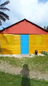 un edificio amarillo y rojo con techo rojo en Isla diablo cabañas en la orilla del mar baño compartido, en Cagantupo