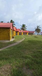 a row of houses with red roofs in a field at Isla diablo cabañas en la orilla del mar baño compartido in Cagantupo