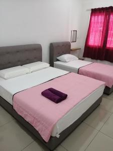 2 bedden in een kamer met paarse lakens bij HOMESTAY PD ERA in Port Dickson