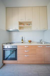 uma cozinha com armários brancos, um fogão e um lavatório em Apartmani Bonaca em Tivat