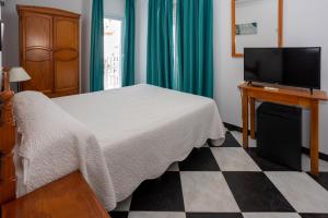 a bedroom with a bed and a flat screen tv at Hotel Oasis in Conil de la Frontera