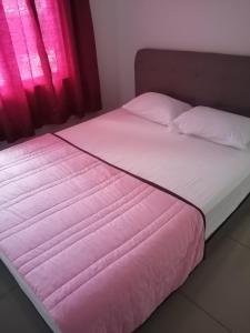 een bed met roze lakens en kussens naast een raam bij HOMESTAY PD ERA in Port Dickson
