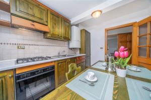 a kitchen with wooden cabinets and a table with pink tulips at Penthouse Central apartments vista Monte Priesnig in Tarvisio