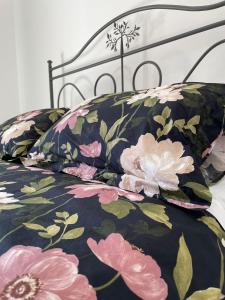 un letto con copriletto e cuscini floreali neri e rosa di la casa nel vicolo ad Ascea