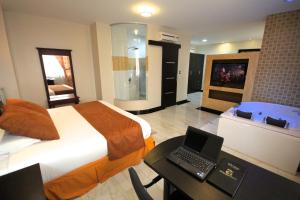a bedroom with a bed and a desk with a laptop at Hotel Golden Vista in Santo Domingo de los Colorados