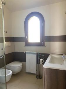 łazienka z toaletą, umywalką i oknem w obiekcie villetta con terrazza w mieście Posada +14 zdjęć
