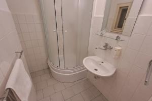 een witte badkamer met een douche en een wastafel bij Comfortable apartment sleeps 6 in Praag