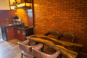 een kamer met een houten tafel met stoelen en een bakstenen muur bij Pariban Hotel in Berastagi