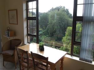 a table and chairs in a room with a large window at Ascot Gardens Self Catering in Cape Town
