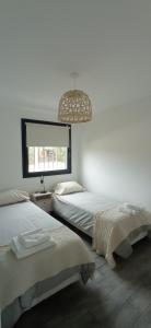 1 dormitorio con 2 camas y lámpara de araña en Casa terraza Quequén en Quequén