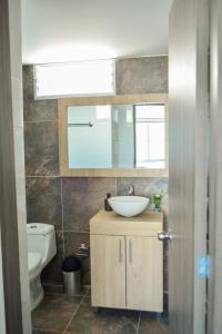 ein Badezimmer mit einem Waschbecken, einem Spiegel und einem WC in der Unterkunft Apartamentos cómodos en Milan zona G in Manizales