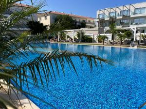 a large blue swimming pool next to a building at Mythical Sands Resort - Good Vibes Apartment in Paralimni