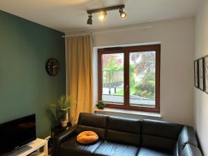 a living room with a black leather couch and a window at Warsaw Mokotów Apartments ABC by Renters in Warsaw