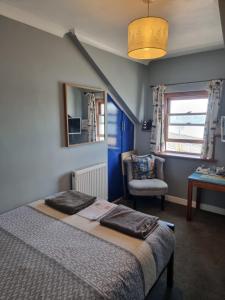 a bedroom with a bed and a chair and a window at The Hut Wales - A Sea Front Inn in Holyhead