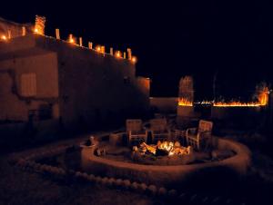 een vuurplaats met stoelen en 's nachts verlichting bij Friendo's House & Hot Spring in Siwa