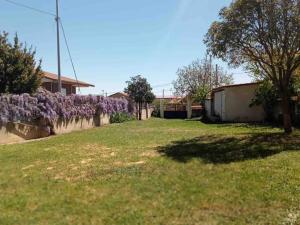 een tuin met een steunmuur met paarse struiken bij Casa El Lloreu in Antimio de Abajo
