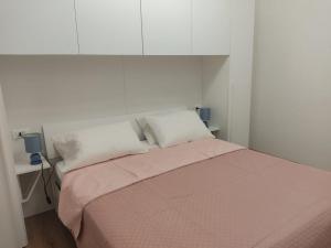 a white bedroom with a bed with a pink blanket at Casa Vacanze Lungomare in Piombino