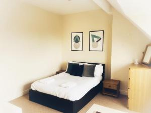 a bedroom with a bed with white sheets and black pillows at Views over the Peak District Apartment with WIFI in Sheffield