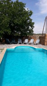 a blue swimming pool with two chairs and a tree at Near Yerevan Serlinhouse in Oshakan