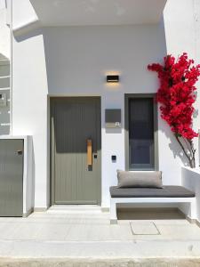 a bench next to a door with a red plant at SunSal Luxury Studios - Earth in Naousa