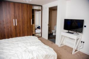 een slaapkamer met een bed en een flatscreen-tv bij Beautiful 5 Bedroom House in Glasgow in Cambuslang