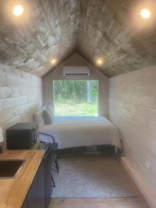 タラホーマにあるWhiskey Woods Retreatのベッドと窓が備わる小さな客室です。