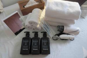 大阪市にあるSUNRISE APT 新大阪駅から徒歩5分観光都市へのアクセス抜群Simply Guest Room Shin-Osakaのベッドの上にタオルとバスアメニティを積み重ねます。