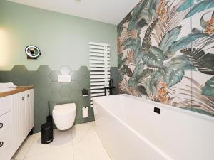 ein Badezimmer mit einer Badewanne und einem Wandgemälde aus Pflanzen in der Unterkunft Seebrücke Heringsdorf - Appartement mit 2 Schlafzimmern S20 in Heringsdorf