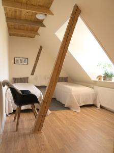 een slaapkamer met een bed en een stoel op zolder bij Akaciegaarden Bed & Breakfast in Hårlev