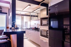 uma cozinha com armários brancos e um balcão preto em Loft Campolim em Sorocaba
