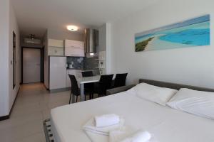 een slaapkamer met een wit bed en een keuken bij Waterfront Apartments with Pool in Novalja